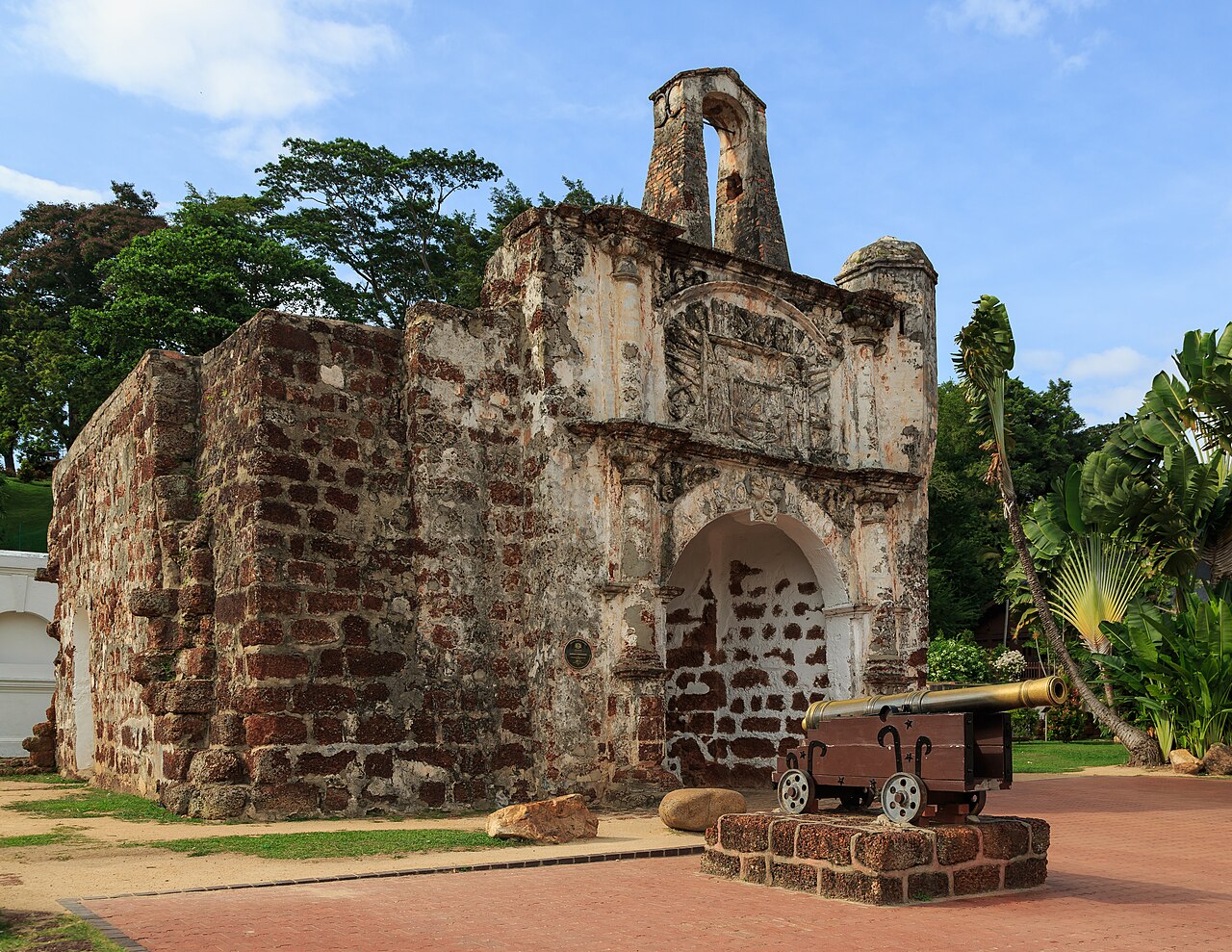 A Famosa heritage gate in Melaka with its stone arch and a cannon in the foreground